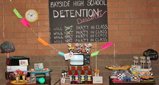 two tables with signs and decorations on them in front of a brick wall that says bayside high school