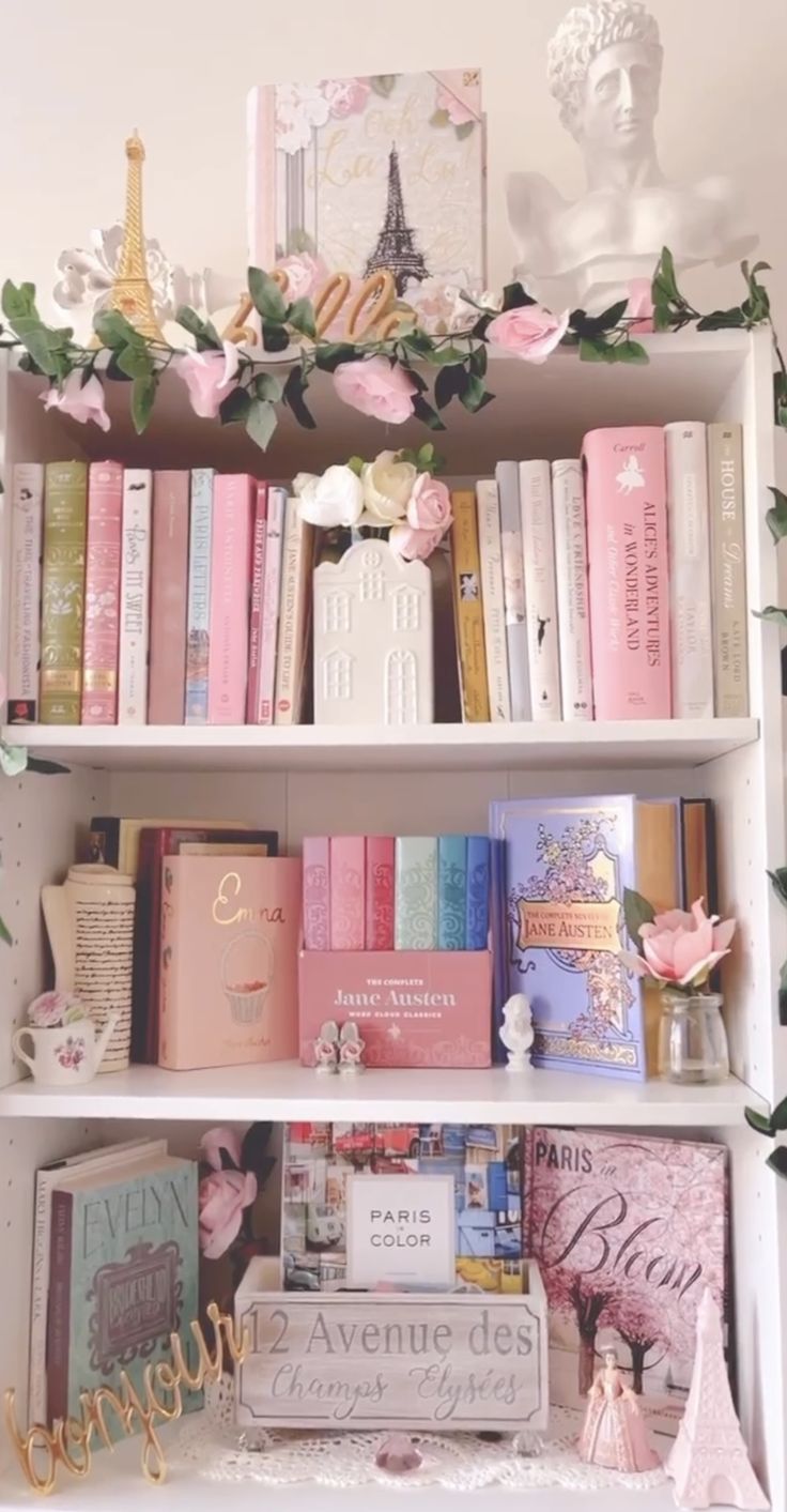 a book shelf filled with lots of books next to a wall covered in pink flowers