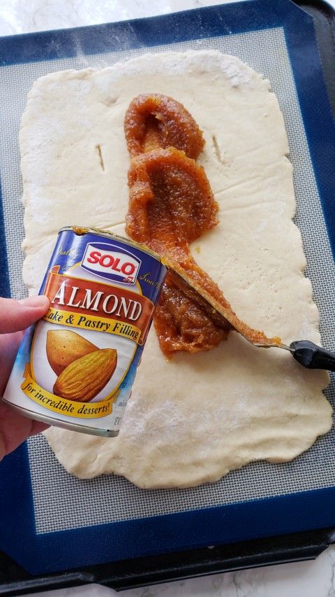 someone is holding a can of almond butter and spreading it on top of some bread