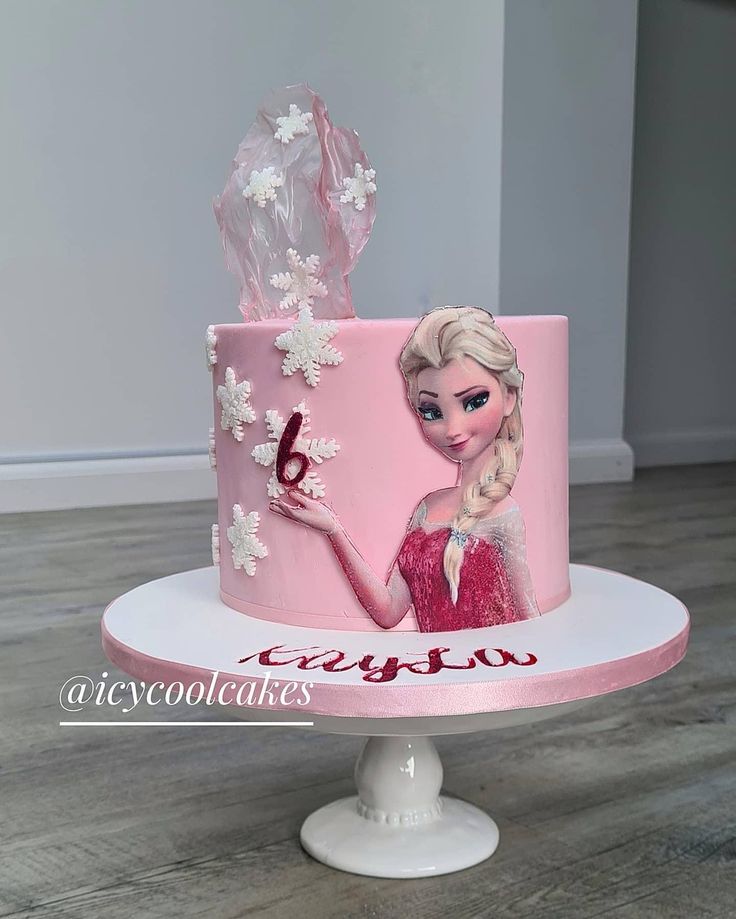 a pink cake decorated with an image of a frozen princess