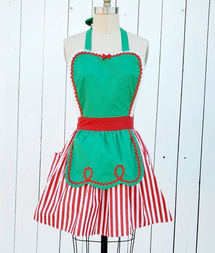 a green apron with red and white stripes is on a mannequin head stand