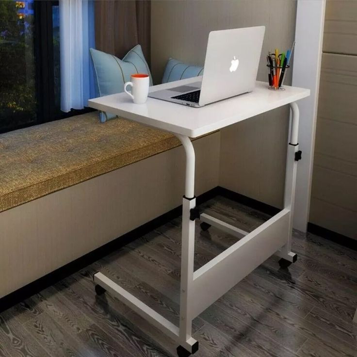 a laptop computer sitting on top of a white desk next to a window sill