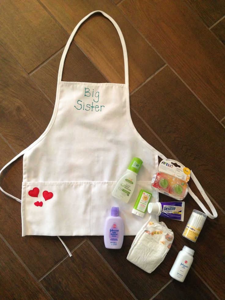 an apron with the words big sister written on it and other items laid out next to it