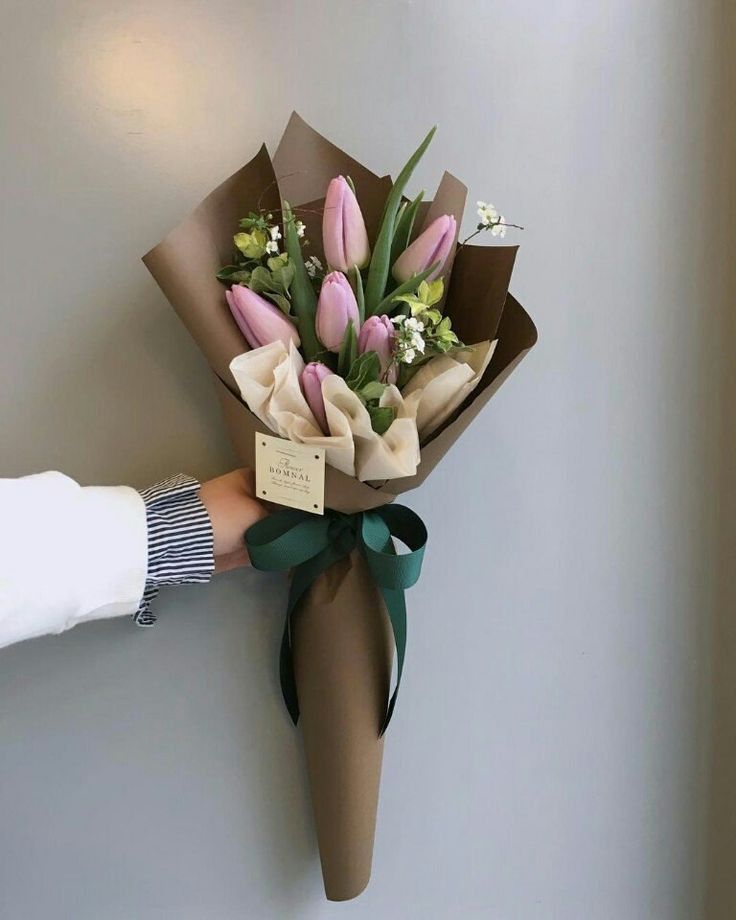 a bouquet of tulips is wrapped in brown paper and tied to the wall