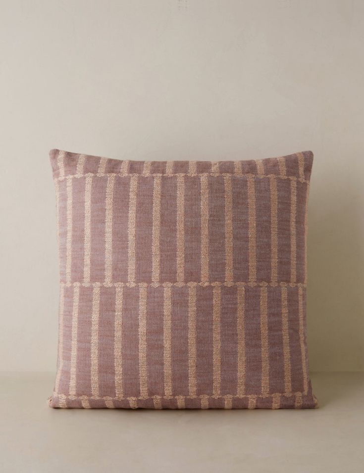 a pink and brown pillow sitting on top of a white table next to a wall