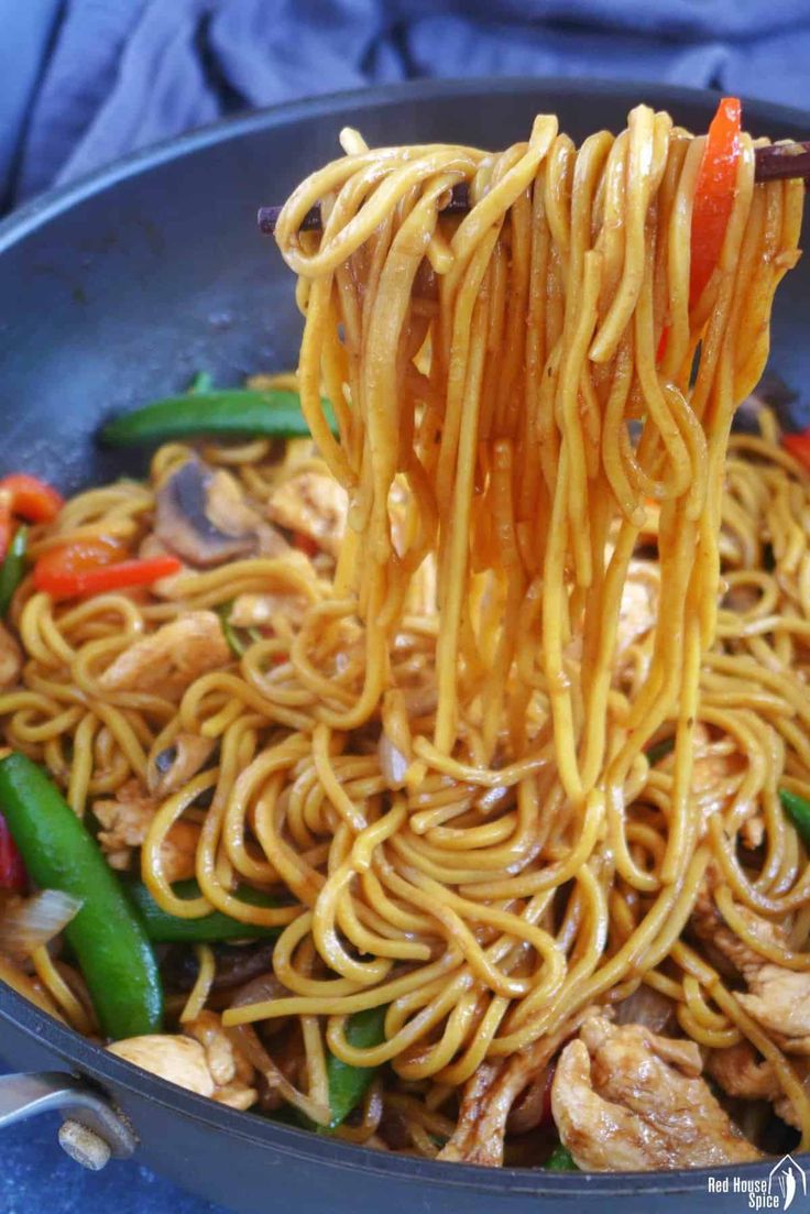 noodles being lifted from a skillet with chopsticks