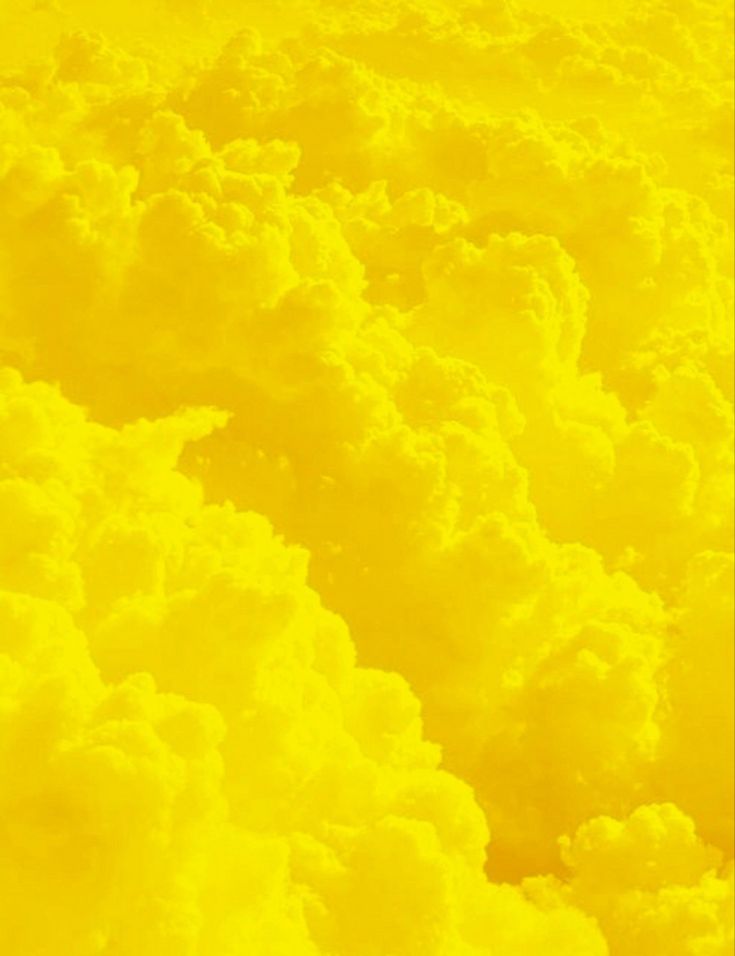 the sky is full of clouds and yellow colors as seen from an airplane's window