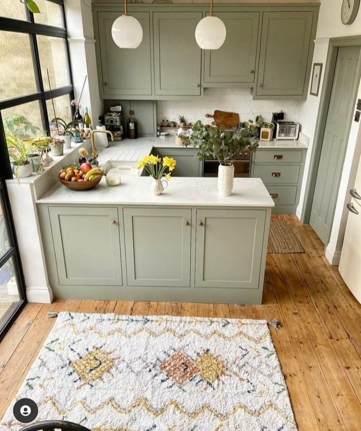 a kitchen with an area rug on the floor and green cabinets in the back ground