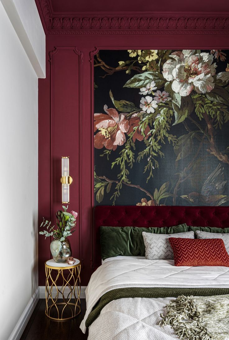 a bed in a room with red walls and floral wallpaper on the headboard