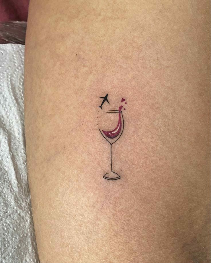 a small wine glass tattoo on the thigh