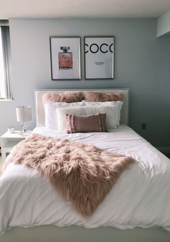 a bed with two pictures on the wall above it and a pink fluffy blanket in front of it