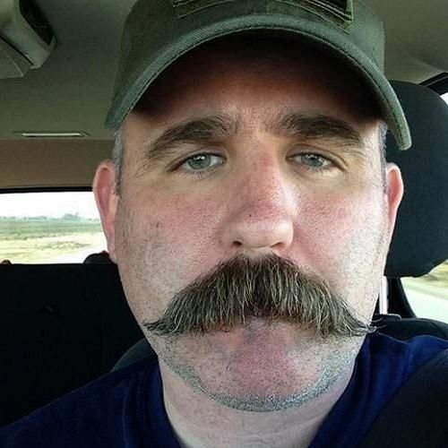 a man with a moustache on his face in the back seat of a car