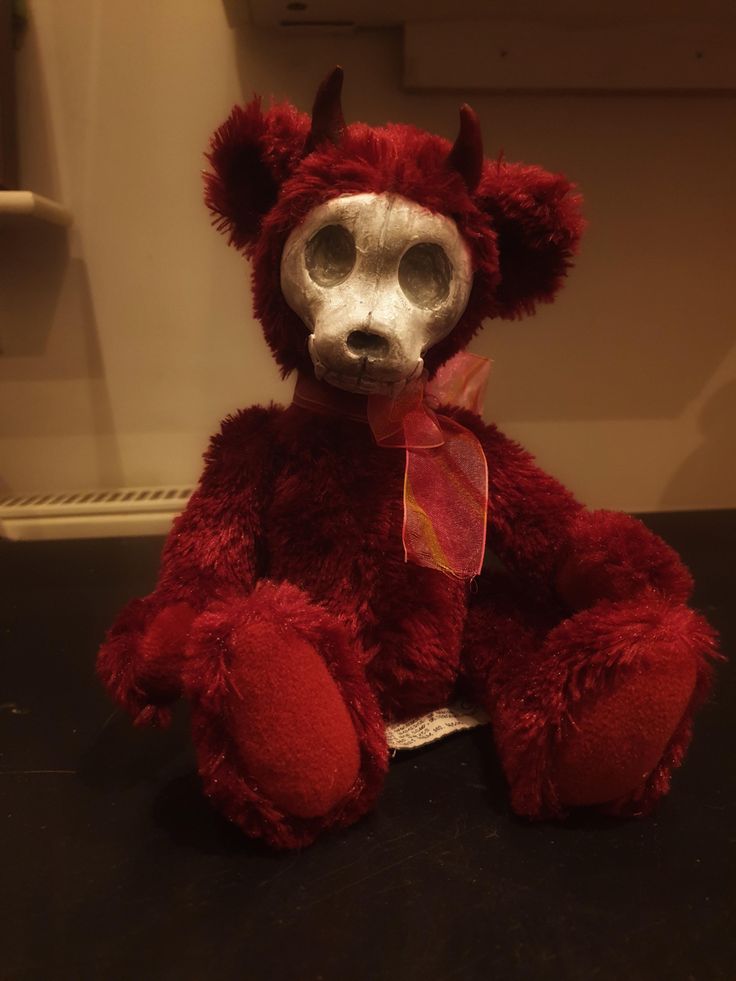 a red teddy bear with white eyes sitting on a table