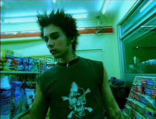 a man with black hair standing in front of a store