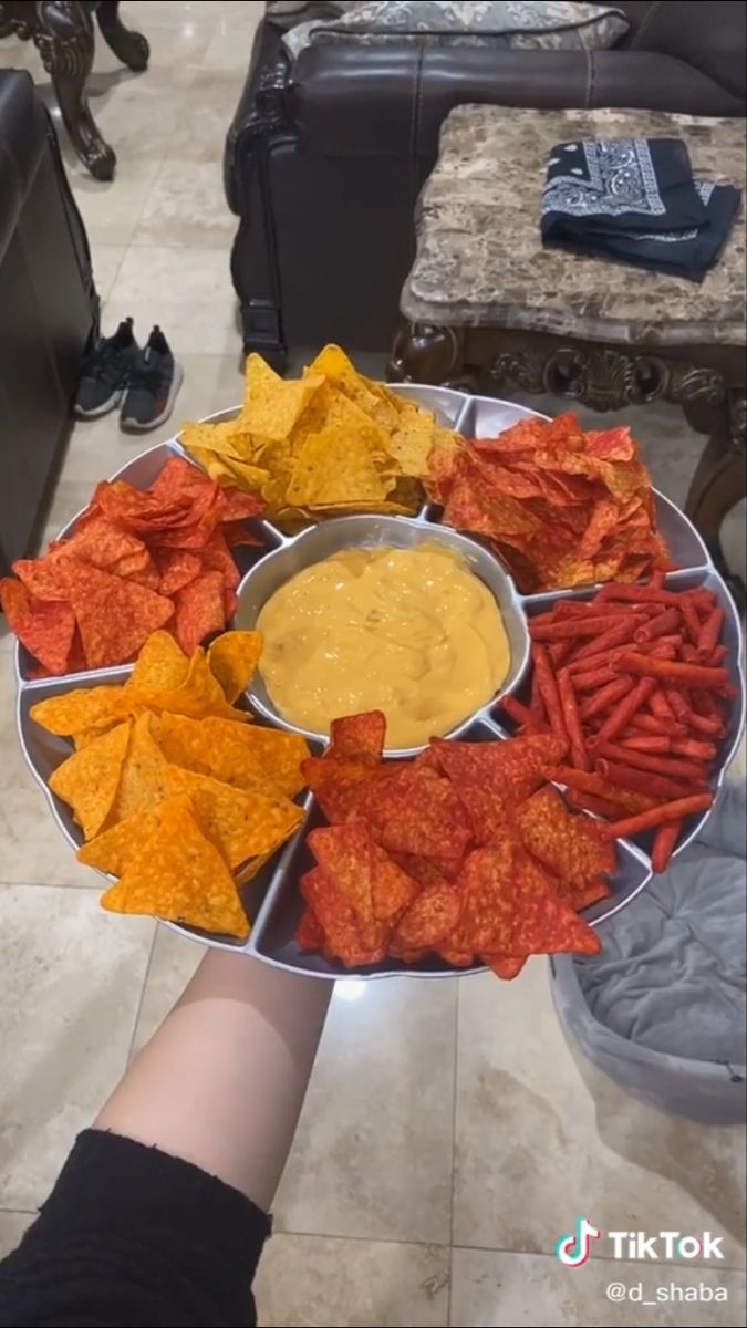 a tray filled with chips and dip next to a person's hand holding it