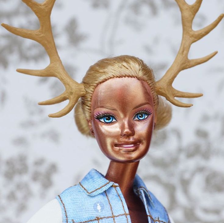 a close up of a doll with antlers on her head and blue eyes,