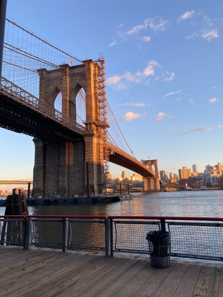 people are standing on the deck looking out at the water and brooklyn bridge in the background