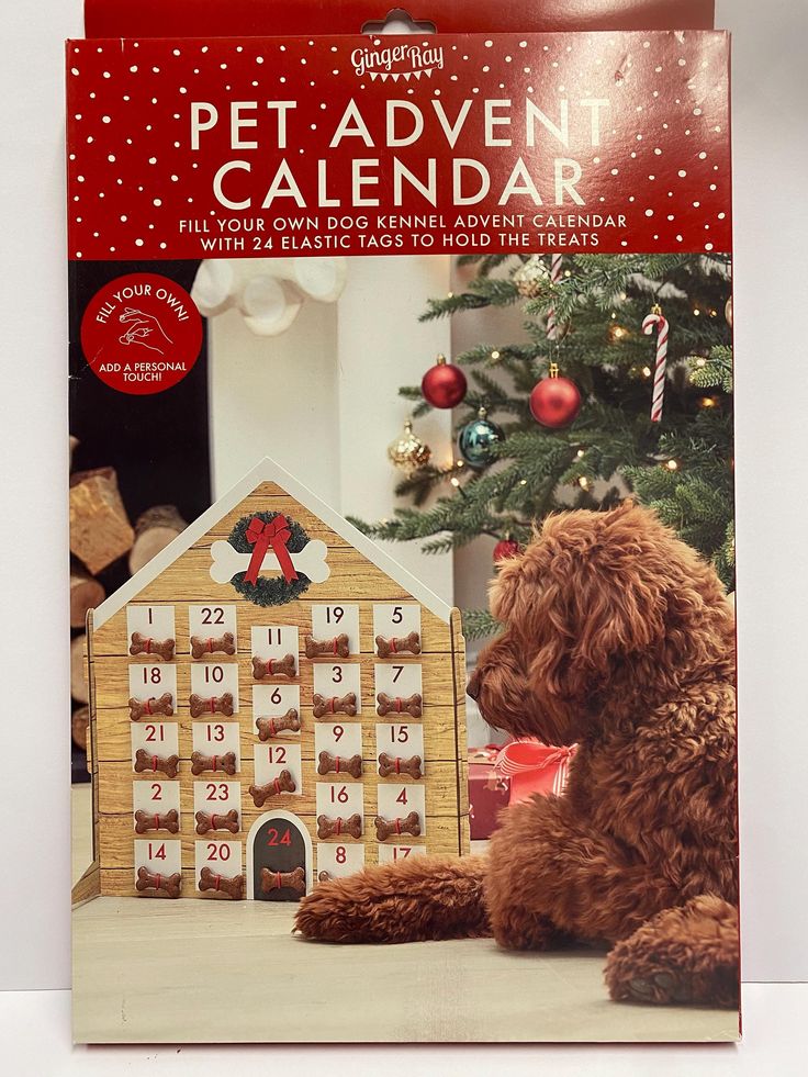 a brown dog sitting in front of a christmas tree with a calendar on it's side