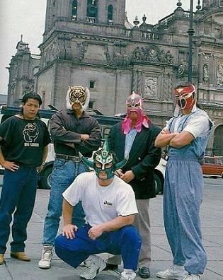 five people wearing masks standing in front of an old building