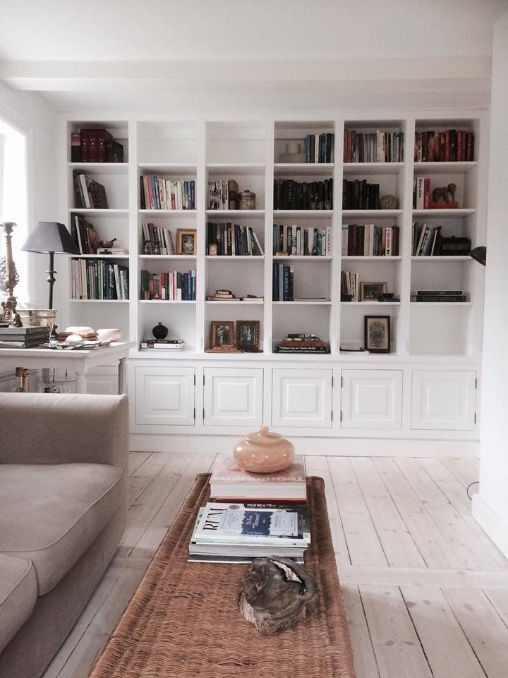 a living room filled with lots of white bookshelves