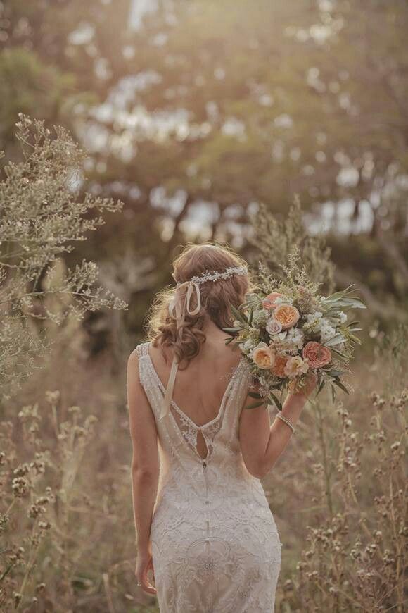 a woman in a white dress is walking through tall grass with flowers on her head