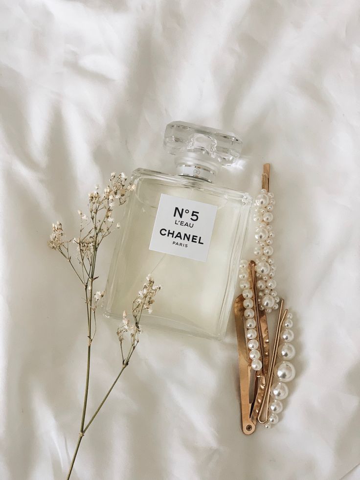 a bottle of chanel no 5 next to some hair pins on a white sheet