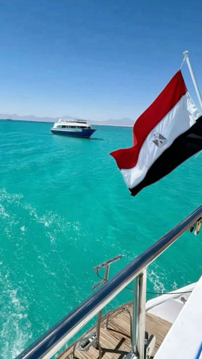 a boat sailing in the ocean with an egyptian flag on it's mast and another boat behind it