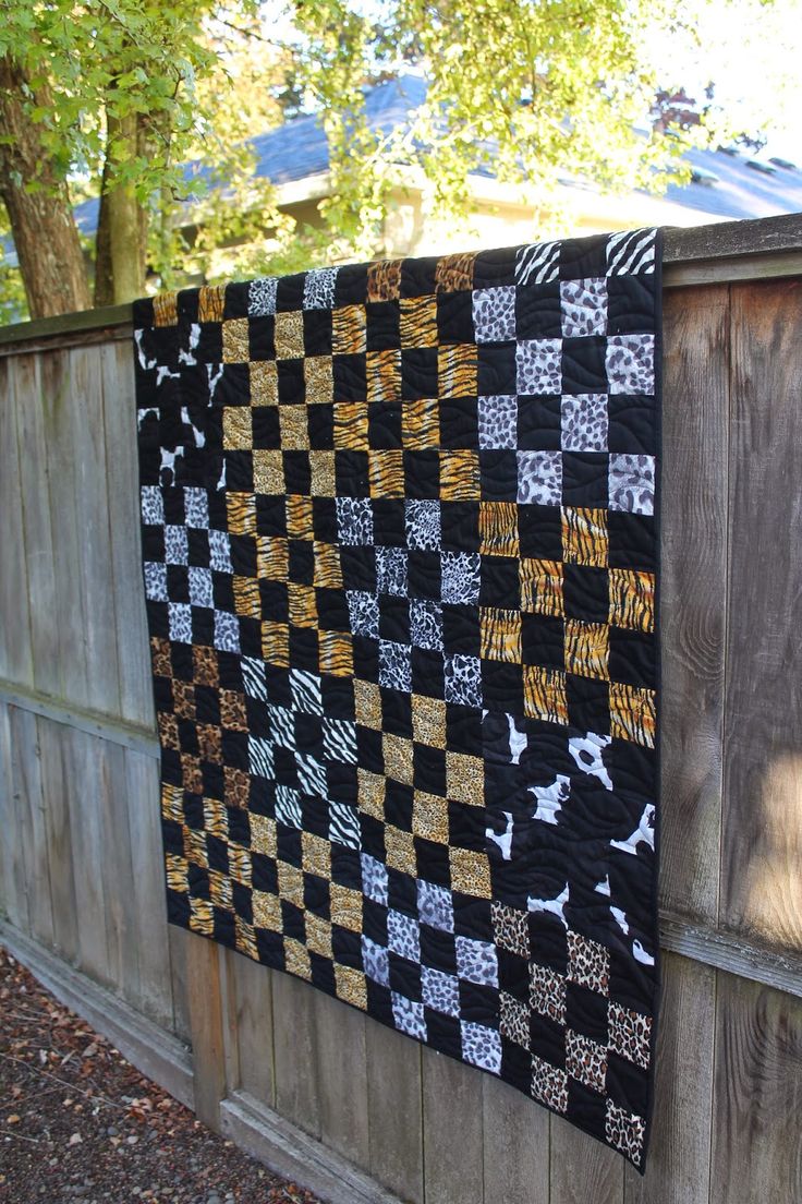 a quilt hanging on the side of a wooden fence