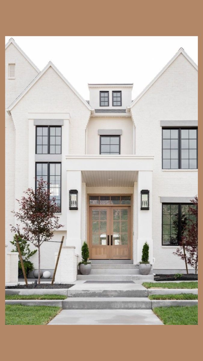 a white house with black windows and steps leading up to the front door is shown