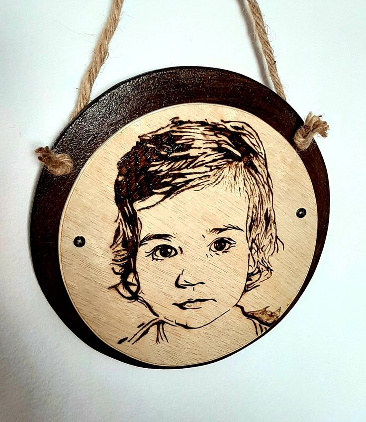 a wooden ornament with a drawing of a child on it's face