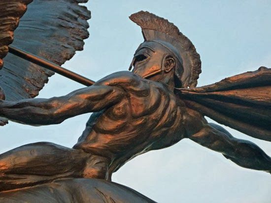 a statue of a man with wings on his back holding a stick in one hand and an umbrella in the other