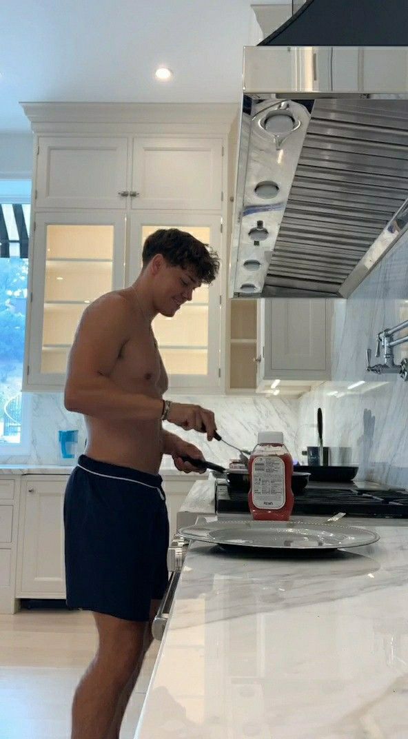 a shirtless man is preparing food in the kitchen