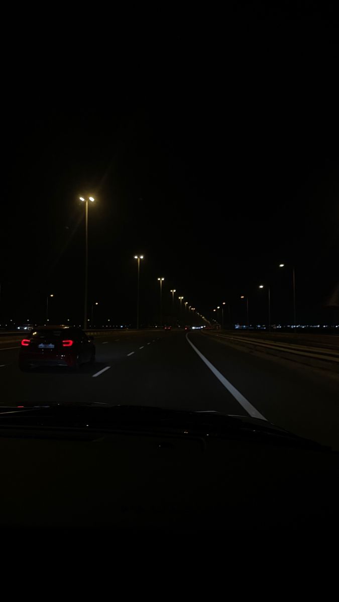 a car driving down an empty highway at night