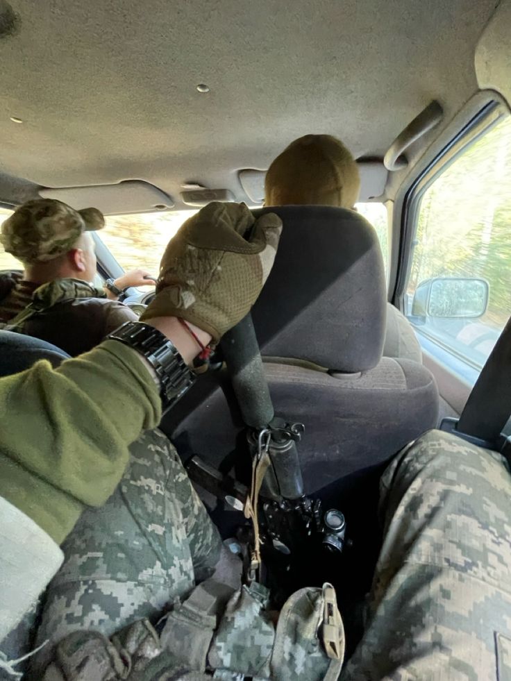 two soldiers sitting in the back seat of a vehicle with their feet on the ground