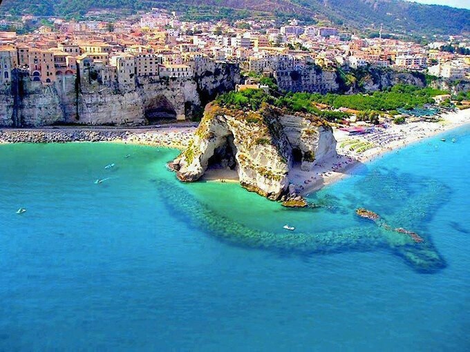 an aerial view of the beach and cliffs in italy, with boats on the water