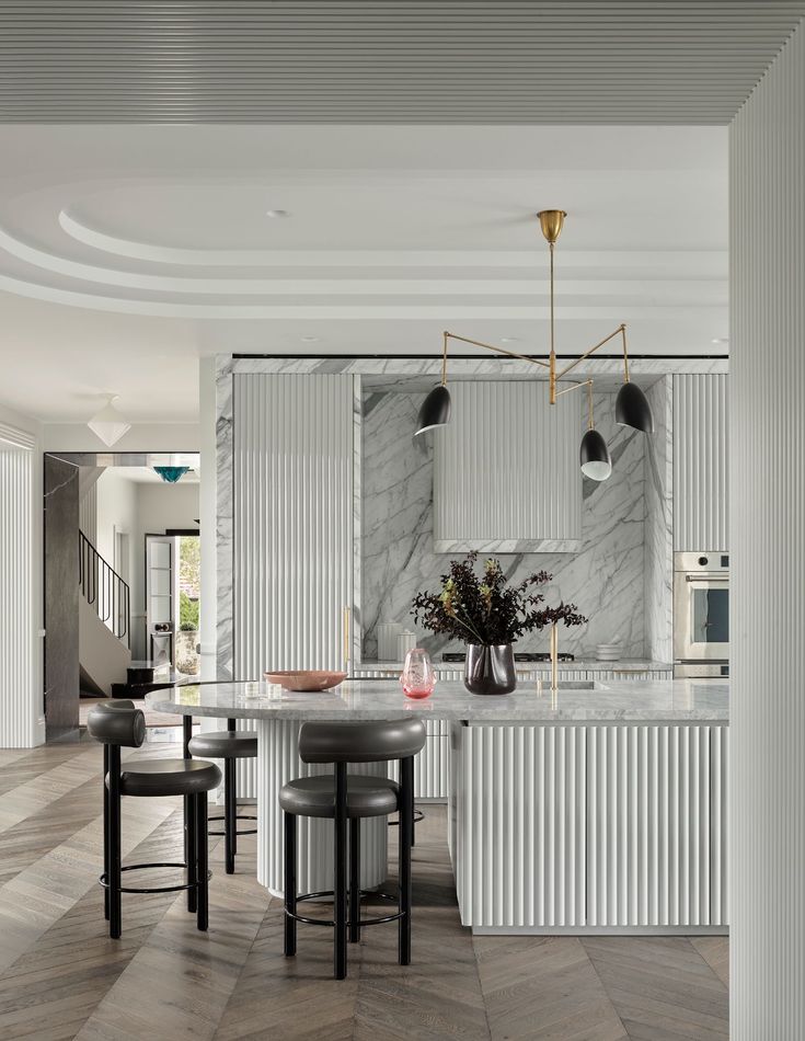 a kitchen with marble counter tops and stools next to an island in the middle