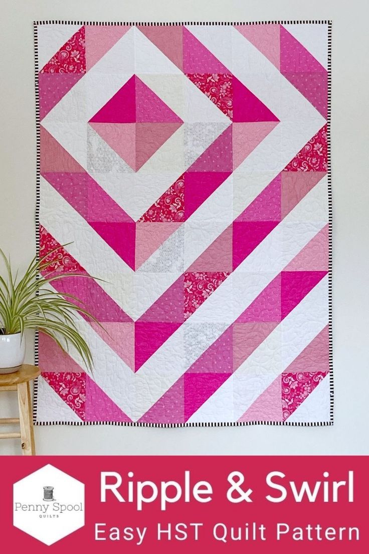 a pink and white quilt hanging on a wall next to a potted green plant