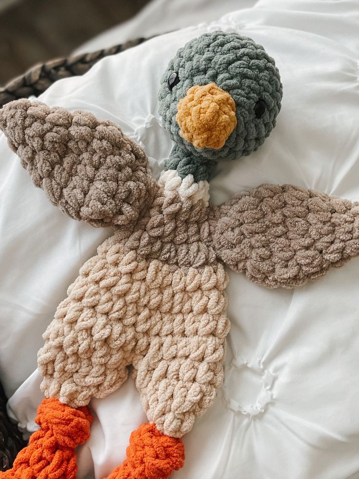 two crocheted stuffed animals laying on top of a white bed next to each other