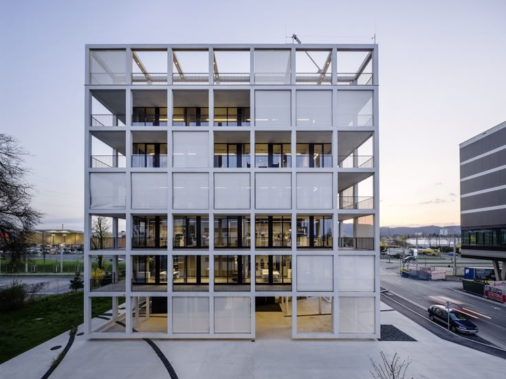 an office building with multiple levels and windows on the outside, in front of a street