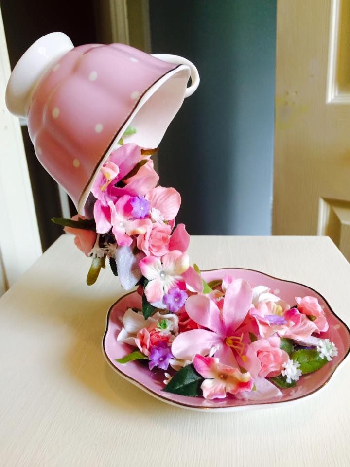 a pink teapot with flowers in it sitting on a table next to a plate