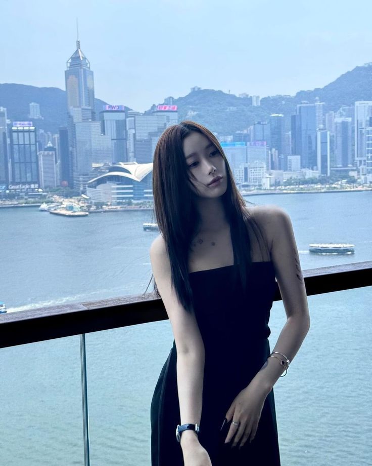 a woman standing on top of a balcony next to a body of water with buildings in the background