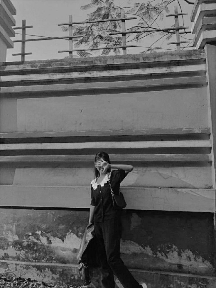 black and white photograph of a woman leaning against a wall with her hand on her head