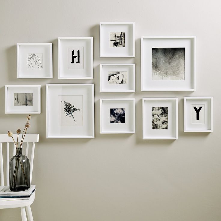 a white chair sitting in front of a wall filled with pictures