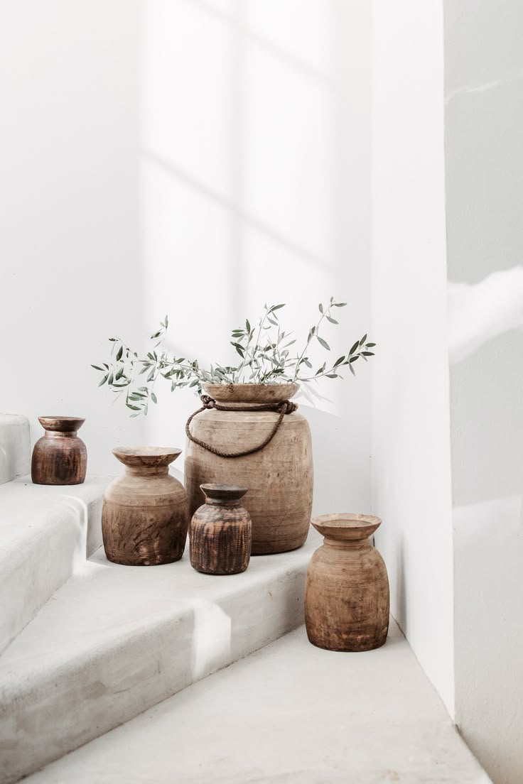 three vases and one plant are sitting on the steps