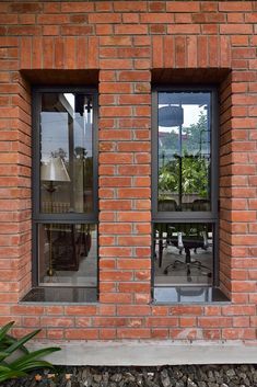 two windows with black frames on a red brick wall next to a table and chairs