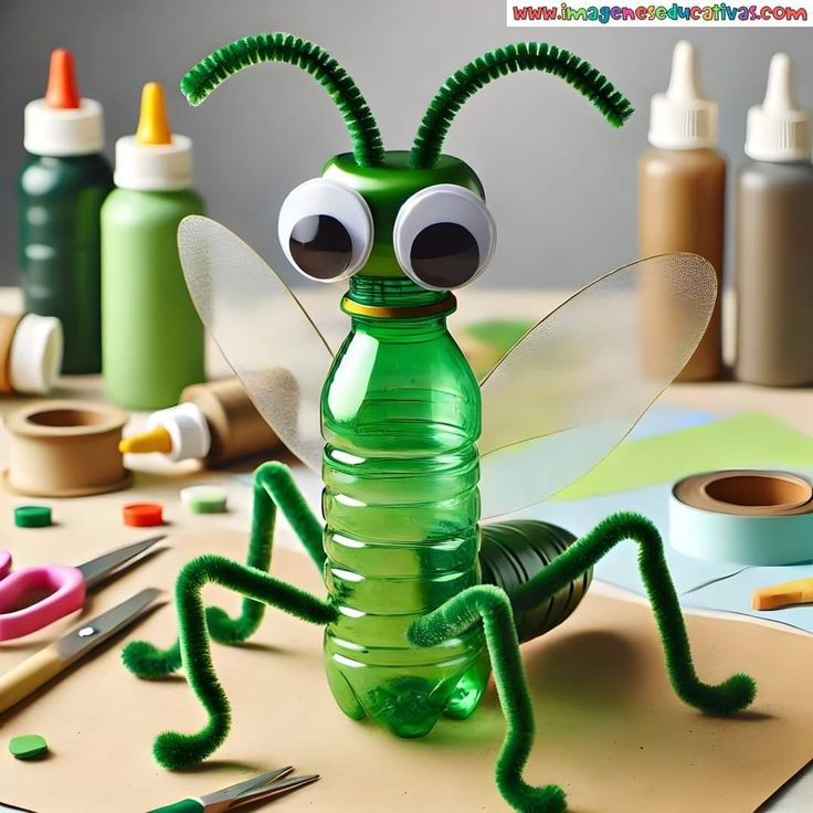 a green insect sitting on top of a table next to craft supplies