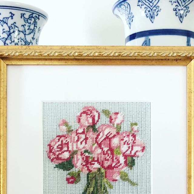 two vases with flowers in them are next to a cross - stitch picture frame