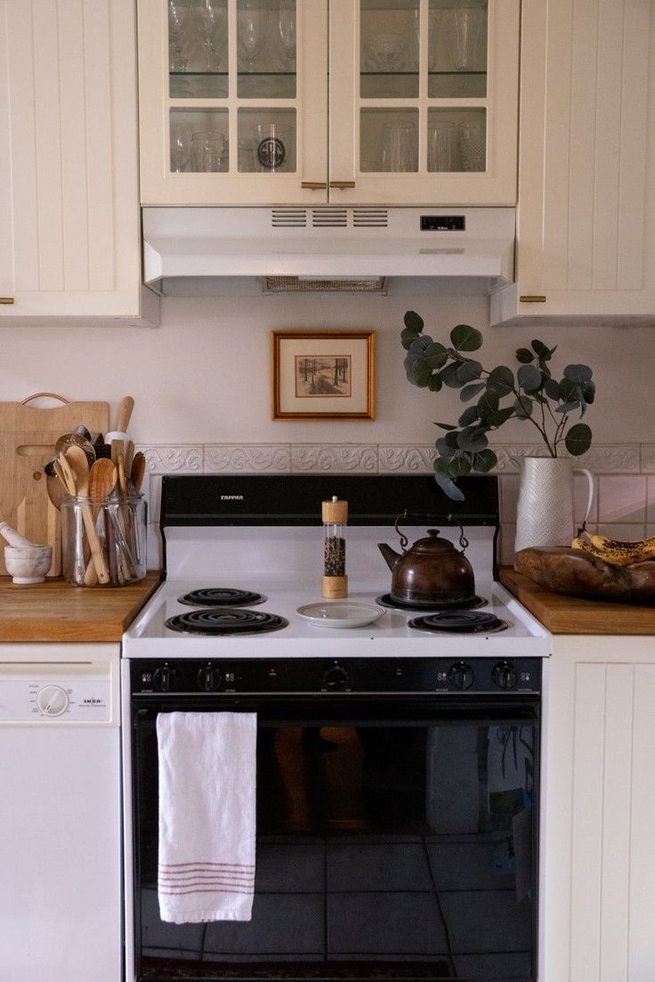 a stove top oven sitting inside of a kitchen next to a counter with utensils on it