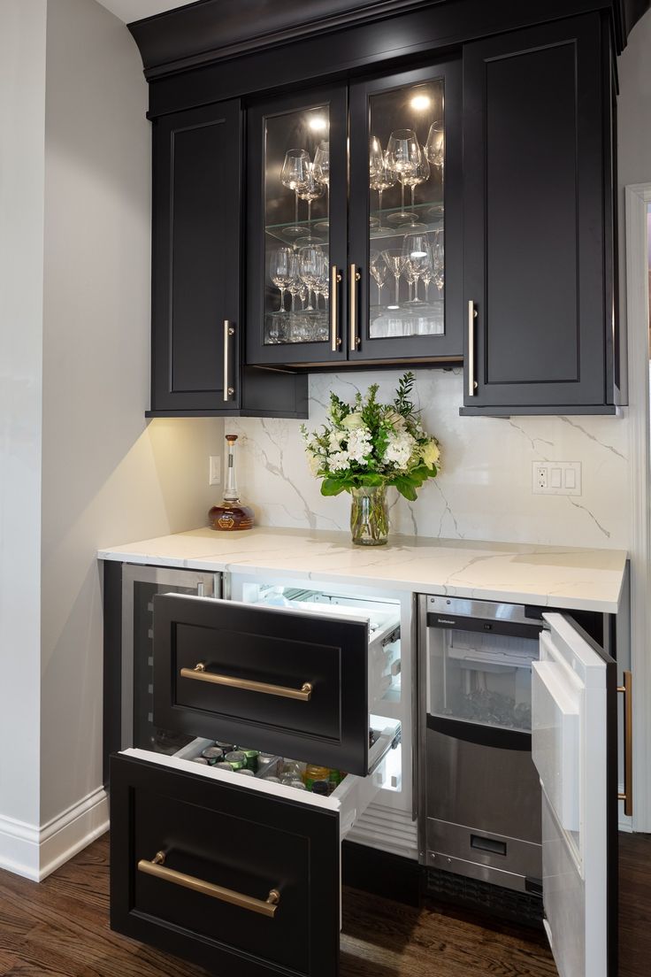 a kitchen with black cabinets and white marble counter tops, an icebox in the center