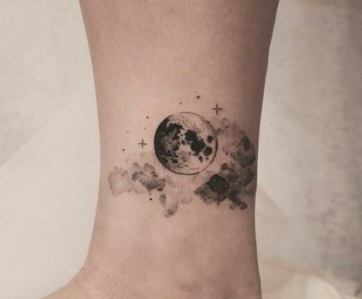 a small tattoo on the ankle of a woman's foot with an image of the moon and stars